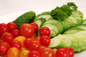 Fresh and colorful display of cherry tomatoes, sliced cucumbers, and parsley.
