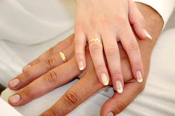 Close-up of a Newlywed Couple's Hands Adorned with Golden Wedding Rings and Elegant Manicures