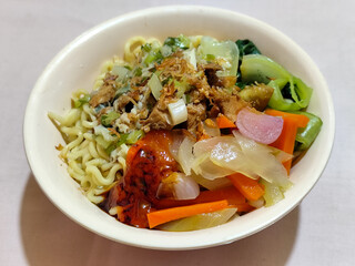 A bowl of delicious chicken noodles, complete with claws, dumplings, chicken pieces on top, traditional Indonesian food.