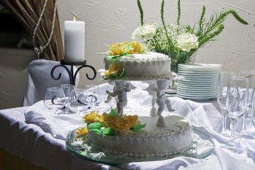 Romantic table setting featuring a tiered wedding cake, candle, and crystal glasses for a celebration.