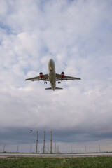 Modern commercial airliner with visible landing gear ascending into a dramatic cloudscape