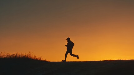 Silhouette of male runner jogging at sunset on hill