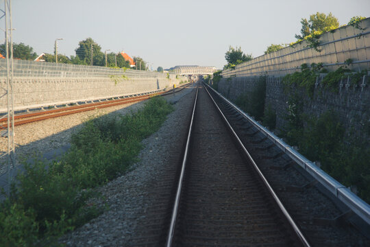 Open Sky Over Railroad Tracks Lined with Sound Walls and Greenery Towards a Horizon Bridge