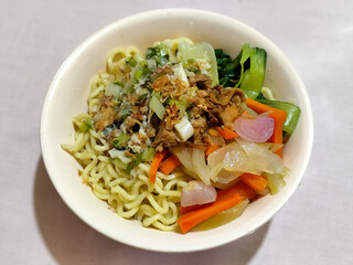 A bowl of delicious chicken noodles, complete with claws, dumplings, chicken pieces on top, traditional Indonesian food.