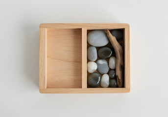 Wooden box with pebbles and driftwood on a transparent background