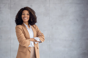 Confident businesswoman standing in a modern office with a smile while crossing her arms
