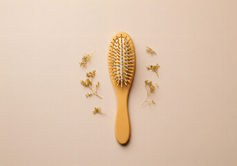 Wooden hairbrush and decorative flowers on a pastel background