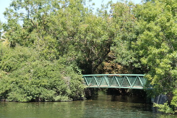 A Green Metal Footbridge Crossing Over a River Tributary.