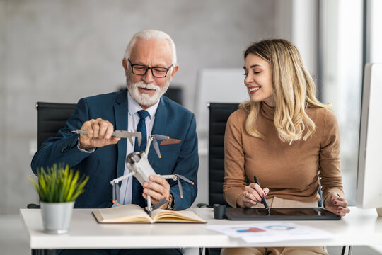 Experienced engineer demonstrates drone mechanics to young designer in modern office setting