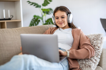 Teenager enjoying online content at home while wearing headphones and relaxing on the sofa in a cozy living room