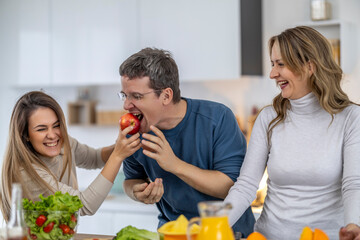 Friends enjoy a fun cooking activity in a bright kitchen while playing with fresh fruits and sharing laughter together