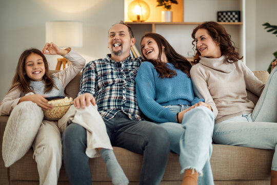 Family enjoying a cozy movie night together on the couch in a warmly lit living room