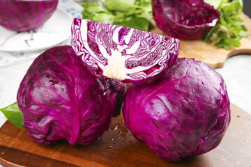 Fototapeta premium Fresh Purple Cabbage Cut in Half with Collard Greens on Wooden Cutting Board