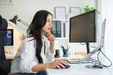 Young woman coding at her desk in a bright, organized home office.