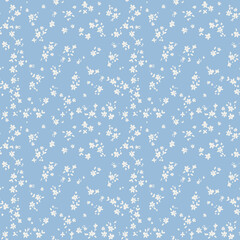 Simple ditsy floral seamless pattern with tiny white flowers on a blue background. Cute and delicate vintage print for textile, fabric, or wallpaper. Spring cottagecore style design.