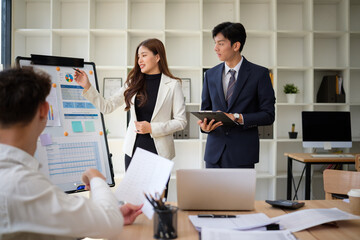 Fototapeta premium Businesswoman presenting data insights on a whiteboard during a meeting.
