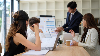 Businessman presenting charts to team during a corporate meeting.