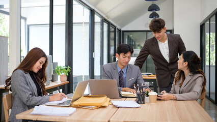 A team of office professionals working together in a modern, well-lit workspace.