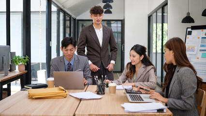 Group of business colleagues working together on a corporate project with laptops and documents.