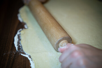 Wooden rolling pin on floured kitchen table. Baking preparation concept.