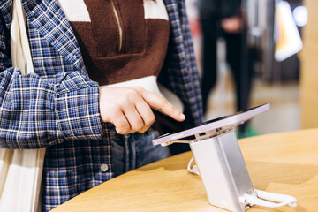 Hand touching screen of tablet display at store, close-up of modern technology.