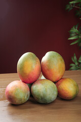 Fresh Ripe Mangoes on Wooden Table with Tropical Plant Background - Organic Fruit Display