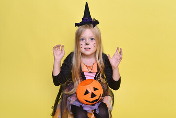 Cute little girl in a witch costume is sitting on a big pumpkin for Halloween.