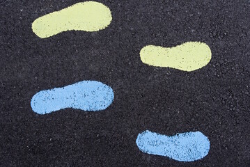 Bunte Fußabdrücke am Asphalt - Fußspuren und Wegweiser