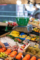 Fresh fruits and nuts, including kish-mish grapes, walnuts, persimmons, mangoes, lychees, white grapes, and strawberries, are for sale at a street market in Paris, France.