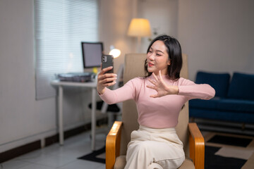 Young asian businesswoman making video call with smartphone in home office