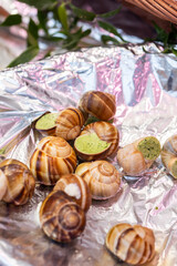 Prepared snails with garlic and butter, known as escargots, are for sale on a sheet of foil at a street seafood market in Paris, France.