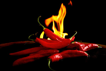 Fotografia art&iacute;stica de pimentas vermelhas frescas em destaque, posicionadas contra um fundo preto, com chamas intensas ao fundo simbolizando ard&ecirc;ncia, sabor picante e intensidade. A composi&ccedil;&atilde;o transm