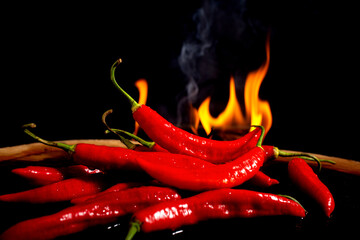 Fotografia art&iacute;stica de pimentas vermelhas frescas em destaque, posicionadas contra um fundo preto, com chamas intensas ao fundo simbolizando ard&ecirc;ncia, sabor picante e intensidade. A composi&ccedil;&atilde;o transm