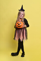 Little girl with blonde hair in a witch costume with a candy cane for Halloween