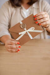 woman hands holding Gift Certificates envelope with seal and bow