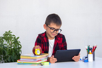 Boy studying remotely. Boy studying with books and his digital tablet at home