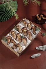 Fresh Shiitake Mushrooms in Wooden Box with Palm Leaves on Terracotta Background