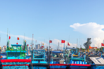 Colorful fishing boats and vietnamese flags in bustling harbor