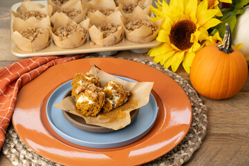 Unwrapped, fresh baked, pumpkin cream cheese muffin with streusel topping on a plate, ready to eat.