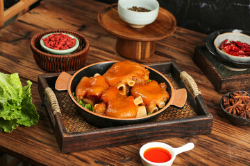 Delicious braised pork knuckle with soy sauce and spices on rustic wooden table, traditional Chinese specialty cuisine