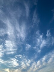 Blue sky with white cirrus clouds on a clear day. Natural background of soft cloudscape