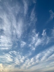 Blue sky with white cirrus clouds on a clear day. Natural background of soft cloudscape