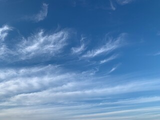 Blue sky with white cirrus clouds on a clear day. Natural background of soft cloudscape