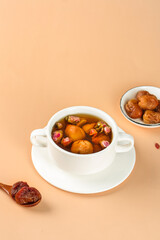 Dried Lychee Fruit Tea with Rose Buds in White Cup on Beige Background