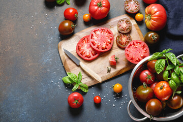 A variety of fresh, ripe tomatoes on a wooden cutting board. A wicker basket contains different colored tomatoes. The scene captures a rustic, farm to table aesthetic. Harvest and cooking concept.