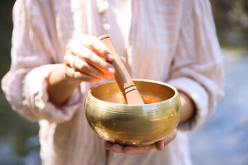 Woman with singing bowl in nature, closeup