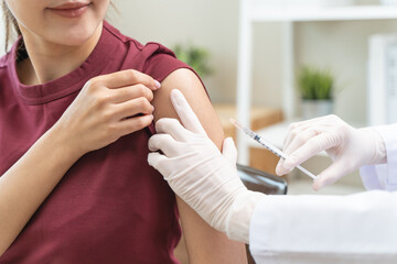 People getting a vaccination to prevent pandemic concept. Woman in medical face mask  receiving a...