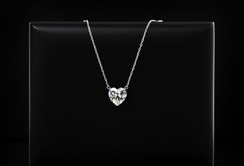 A necklace with a heart pendant is on a black record