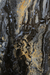 Dark stone surface with unique swirling patterns and hues of gold, gray, and black created by natural mineral formations