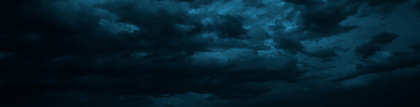 Dramatic sky with heavy clouds. Black dark blue green grey night cloudy sky. Thunderstorm storm rain moonlight wind cyclone hurricane. Ominous frightening fantastic epic. Wide banner. Panoramic.	